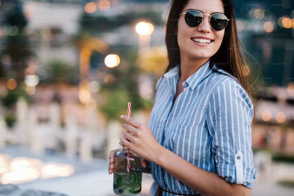 Beautiful young woman smiling and drinking cocktail