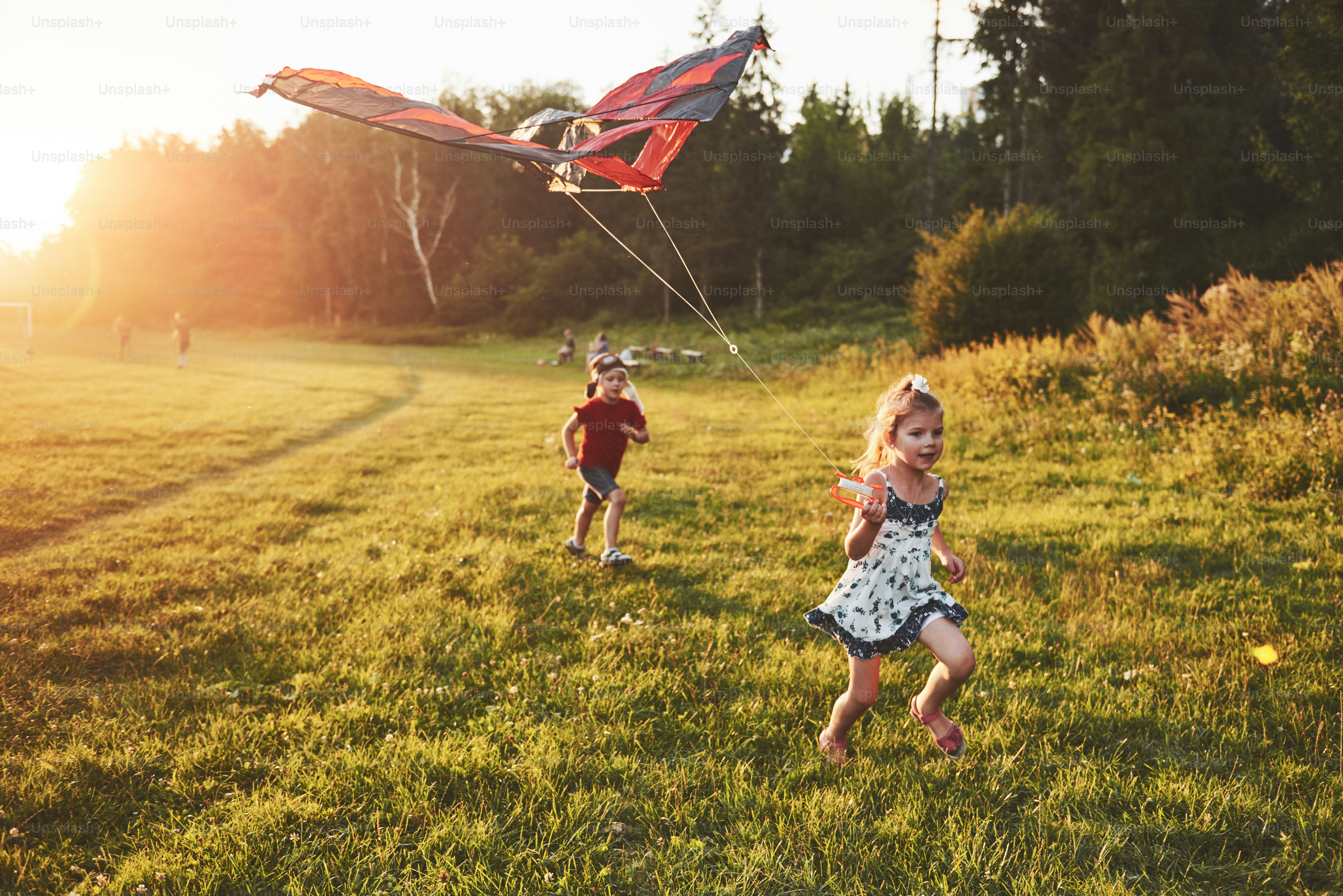 Happy children launch a kite in the field at sunset. Little boy and girl on summer vacation.