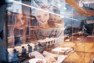 Two happy attractive girls choosing delicious ganaches, praline and chocolates.