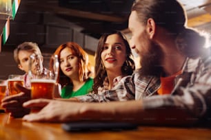 Dark-haired girlfriend. Appealing dark-haired girlfriend with red lips looking at her bearded man in the bar