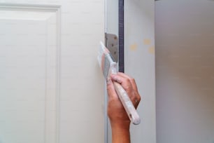 Appaltatore che dipinge di bianco una porta di legno in una nuova casa