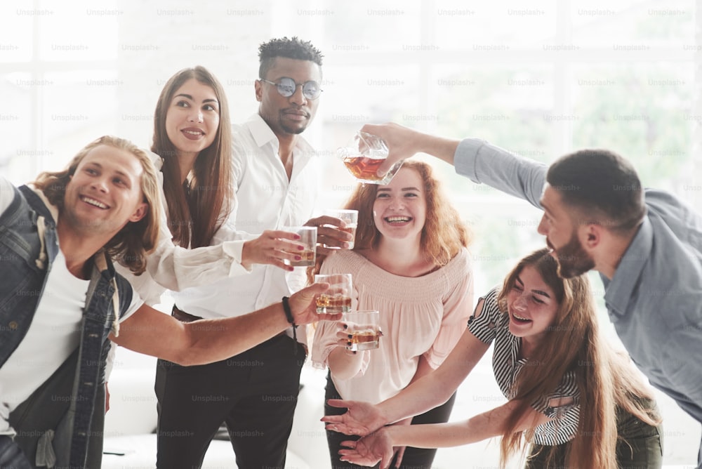 Teammates drinking whiskey and laughing because of successful deal.