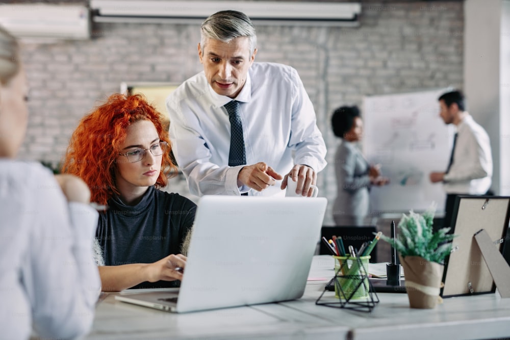 Business colleagues cooperating while working together on computer in modern office.