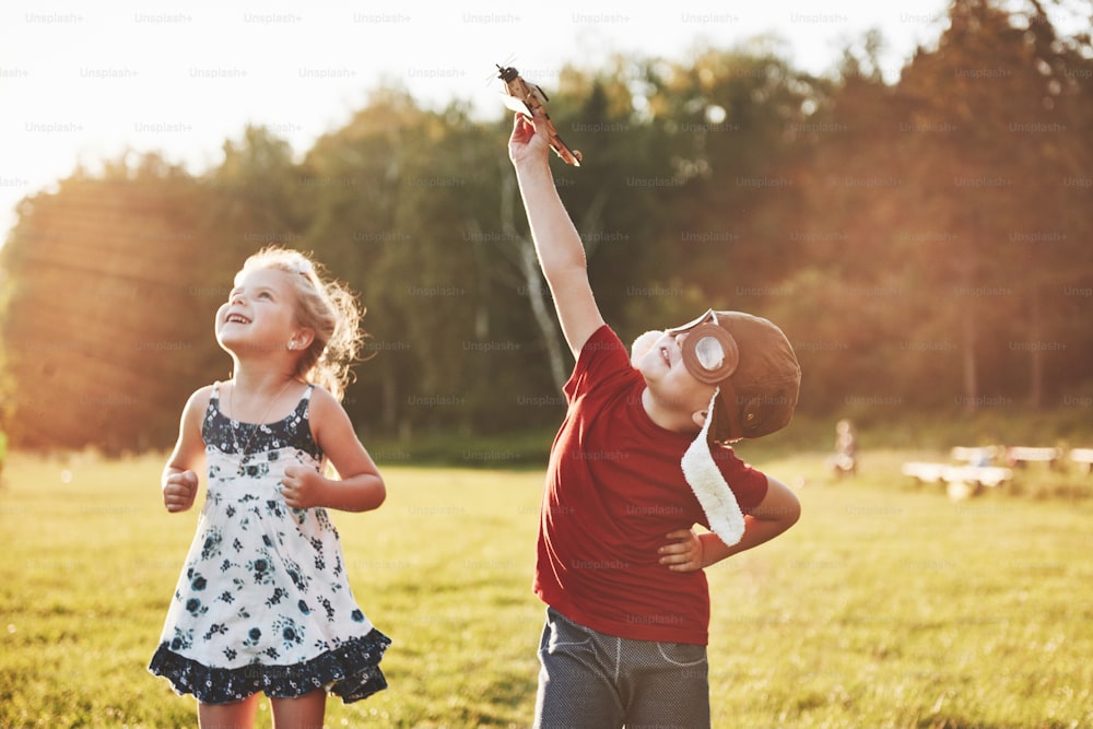 Le frère et la sœur jouent ensemble. Deux enfants jouant avec un avion en bois à l’extérieur.