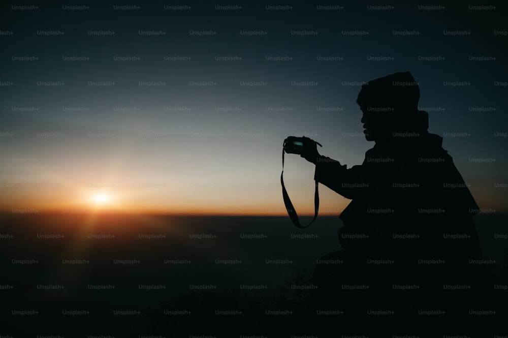 Fotógrafo que toma fotografías en la vista de la montaña con la silueta del amanecer.