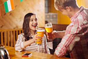 Beer with boyfriend. Beautiful dark-haired woman wearing striped blouse drinking beer with boyfriend