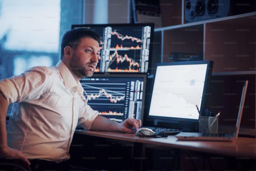 Busy working day. Close-up of young businessman looking at monitor while sitting at the desk in creative office.