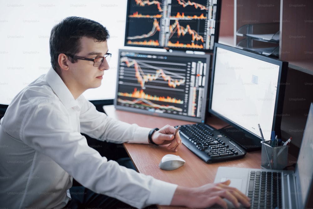Un corredor de bolsa en camisa está trabajando en una sala de monitoreo con pantallas de visualización. Concepto gráfico de las finanzas de Forex que opera en la bolsa de valores. Hombres de negocios que negocian acciones en línea.