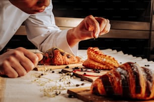 Croissants and puff. Baker decorating croissants and cream puff on wooden plates