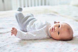 Adorable newborn baby girl lying on her parents' bed at home