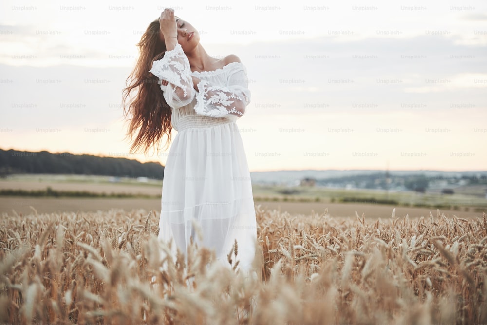 Porträt eines schönen Mädchens in einem weißen Kleid auf dem Weizenfeld.