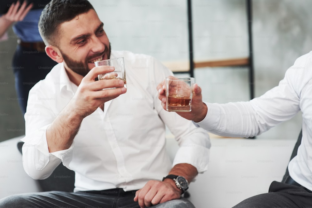 Deux collègues célèbrent les bonnes affaires dans leur entreprise en buvant de l’alcool.