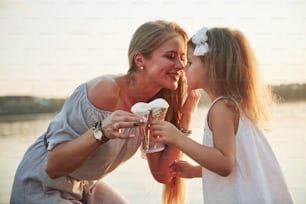 Mother and child eat ice cream in the park at sunset