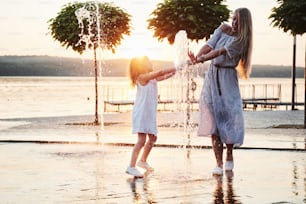 mother with baby near the fountain at sunset.
