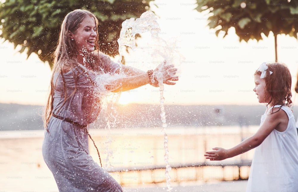 Récupérez l’eau. Par une journée chaude et ensoleillée, la mère et sa fille décident d’utiliser la fontaine pour se rafraîchir et s’amuser avec.