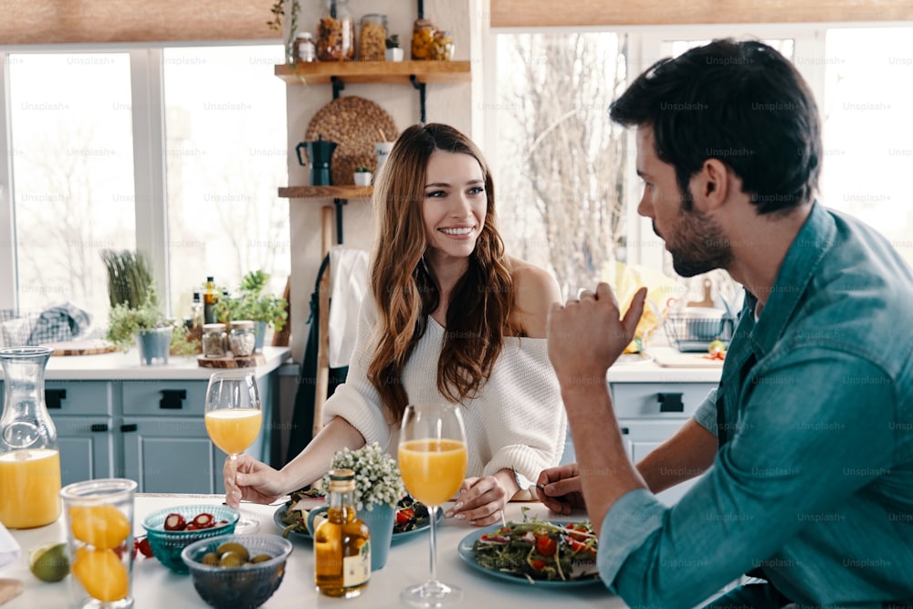 Beautiful young couple enjoying healthy breakfast while sitting in the kitchen at home