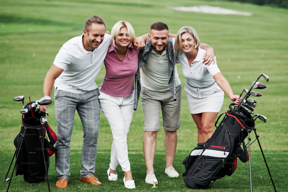 Photo of friends hugging and smiling with golf equipment after the game.