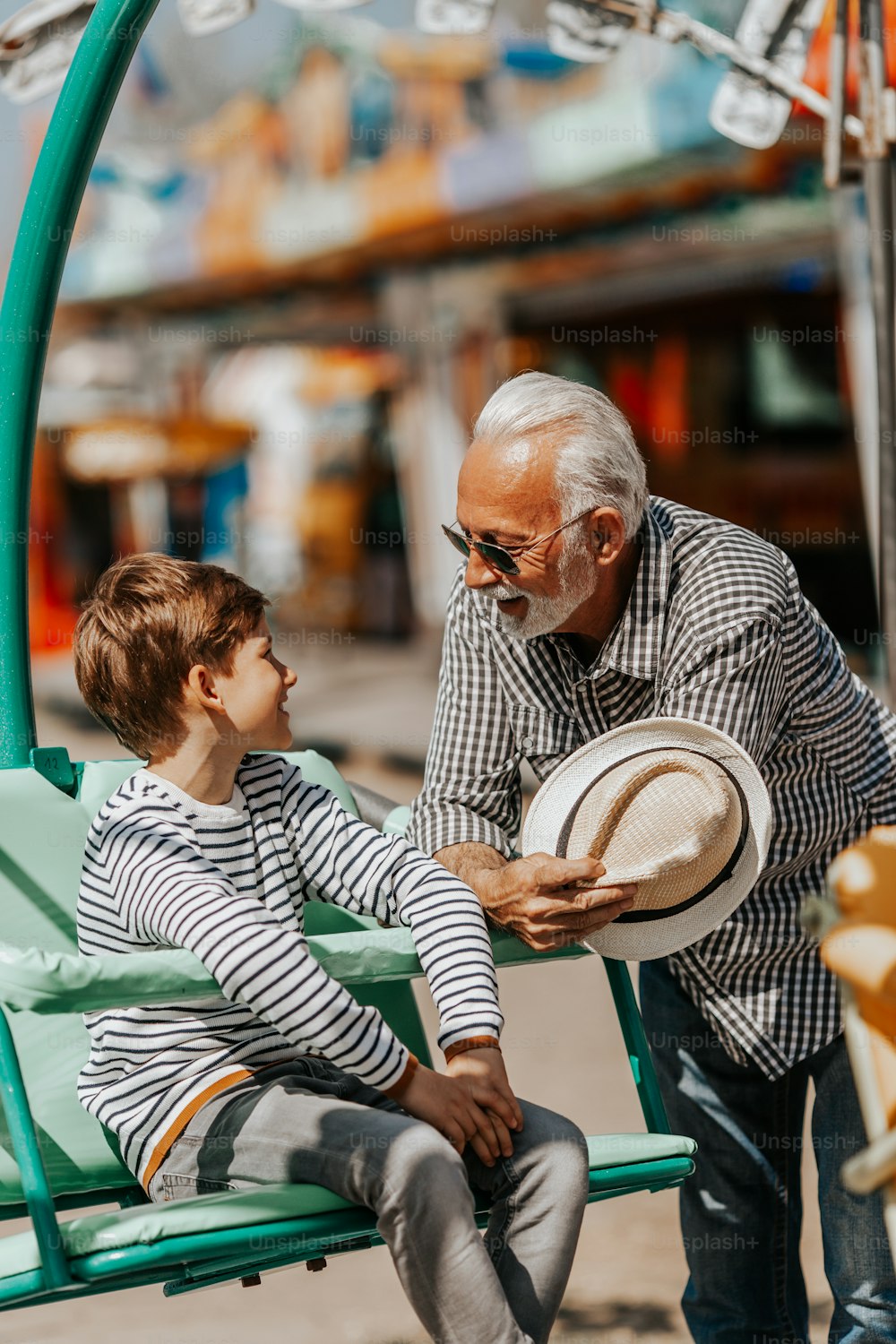 Grandfather and grandson having fun and spending good quality time together in amusement park.