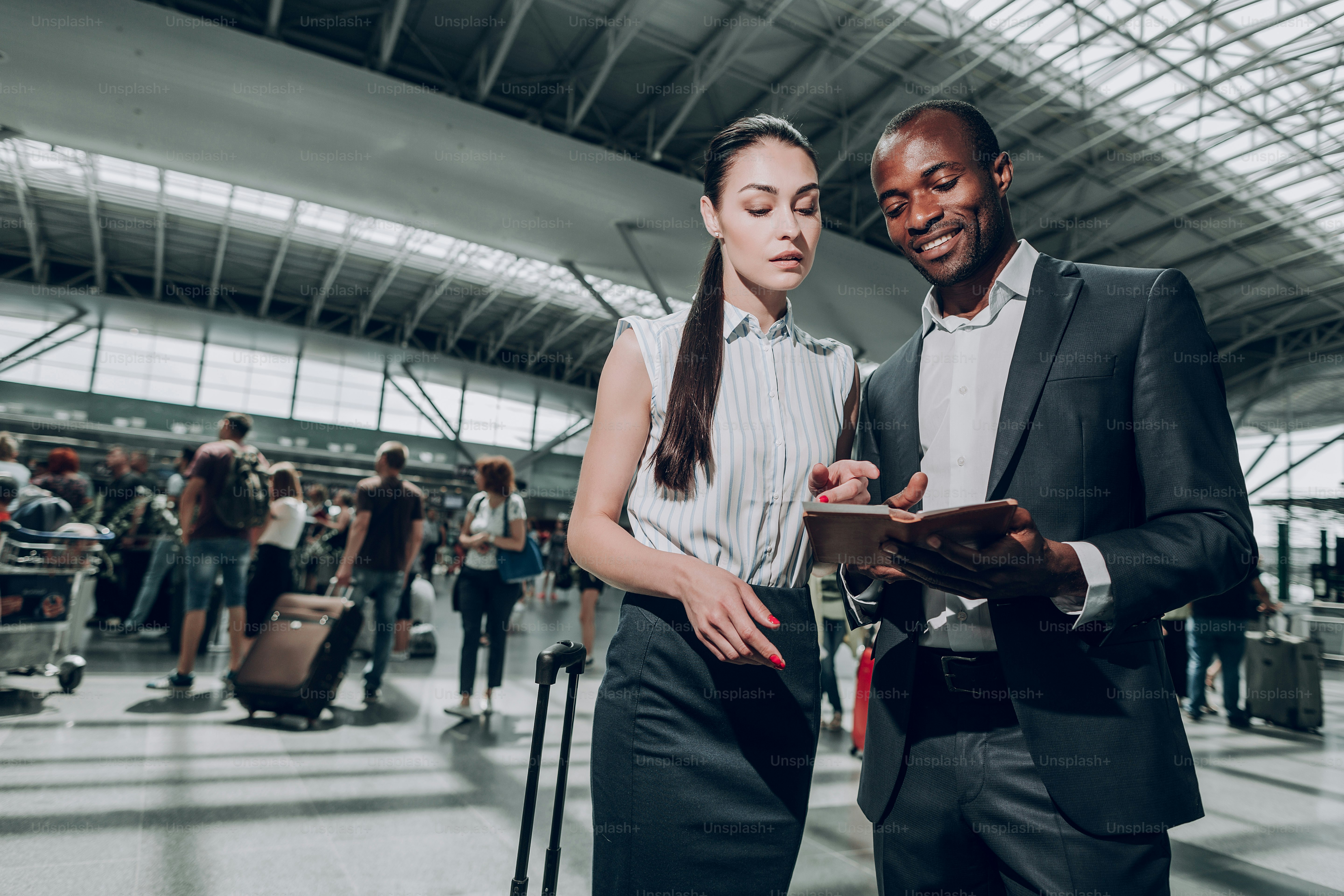 Checking tickets. Waist up portrait of business lady and smiling man reviewing their tickets at the airport