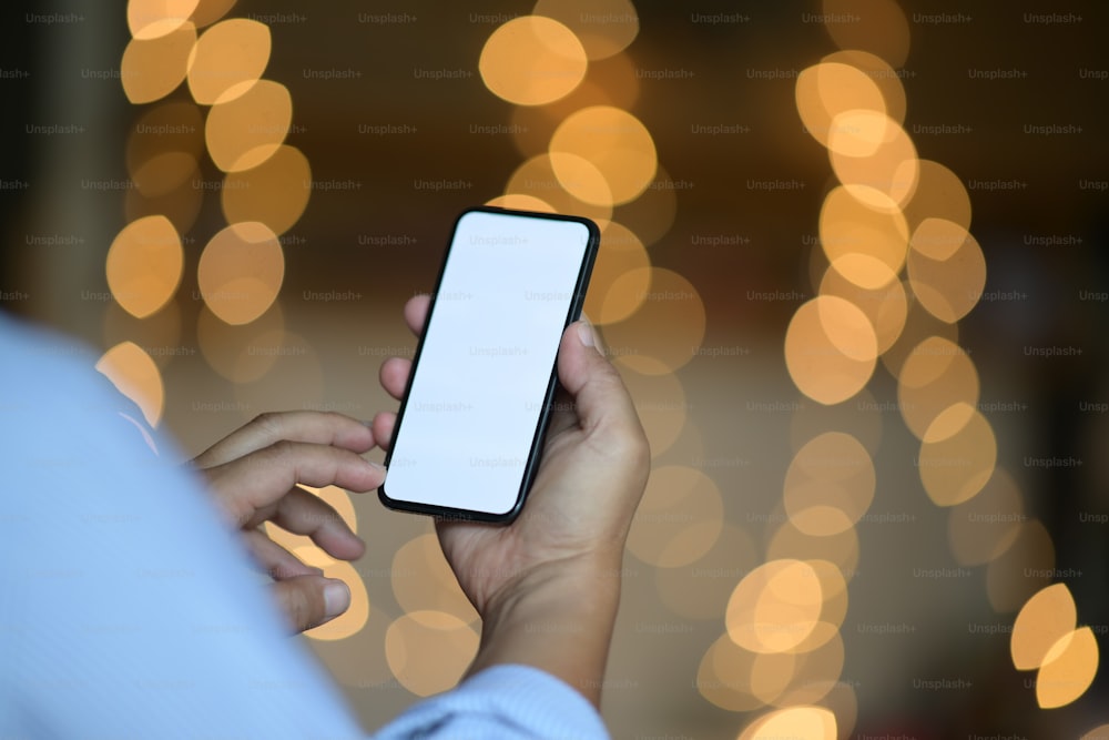 Man hand holding mobile smartphone with blur bokeh background