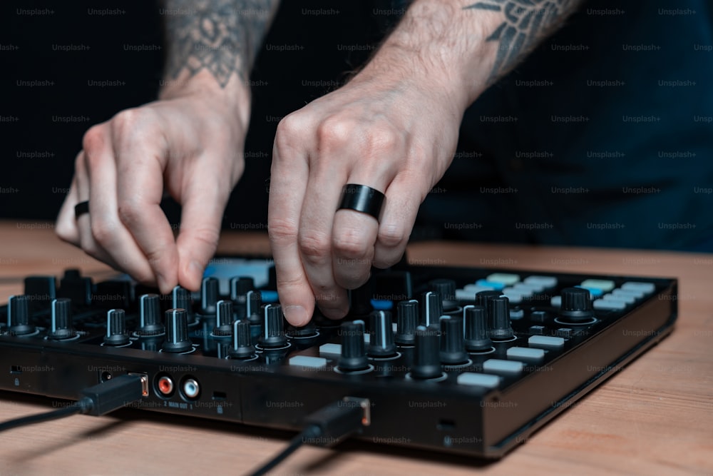Nahaufnahme und beschnittene Foto-Tattoo-Hände von professionellem DJ-Mann kreative Musik im House Room Studio mit schwarzer dunkler Wandeinrichtung. Er verwendet ein räumliches Controller-Instrument