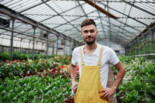 Sentirse de buen humor. Foto de un joven y atractivo granero de pie entre los parterres del jardín con jarrones y otras plantas.