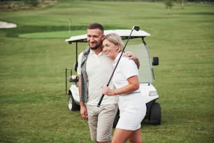 Two professional golfers, a woman and a man go together to the next hole. Lovers hug and smile, they have a date.
