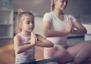 Per la pace e il relax, lo yoga è l'esercizio migliore. Madre e figlia che lavorano yoga.