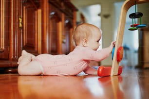 床のおもちゃで遊んでいる女の赤ちゃん。家で幸せな健康な小さな子供