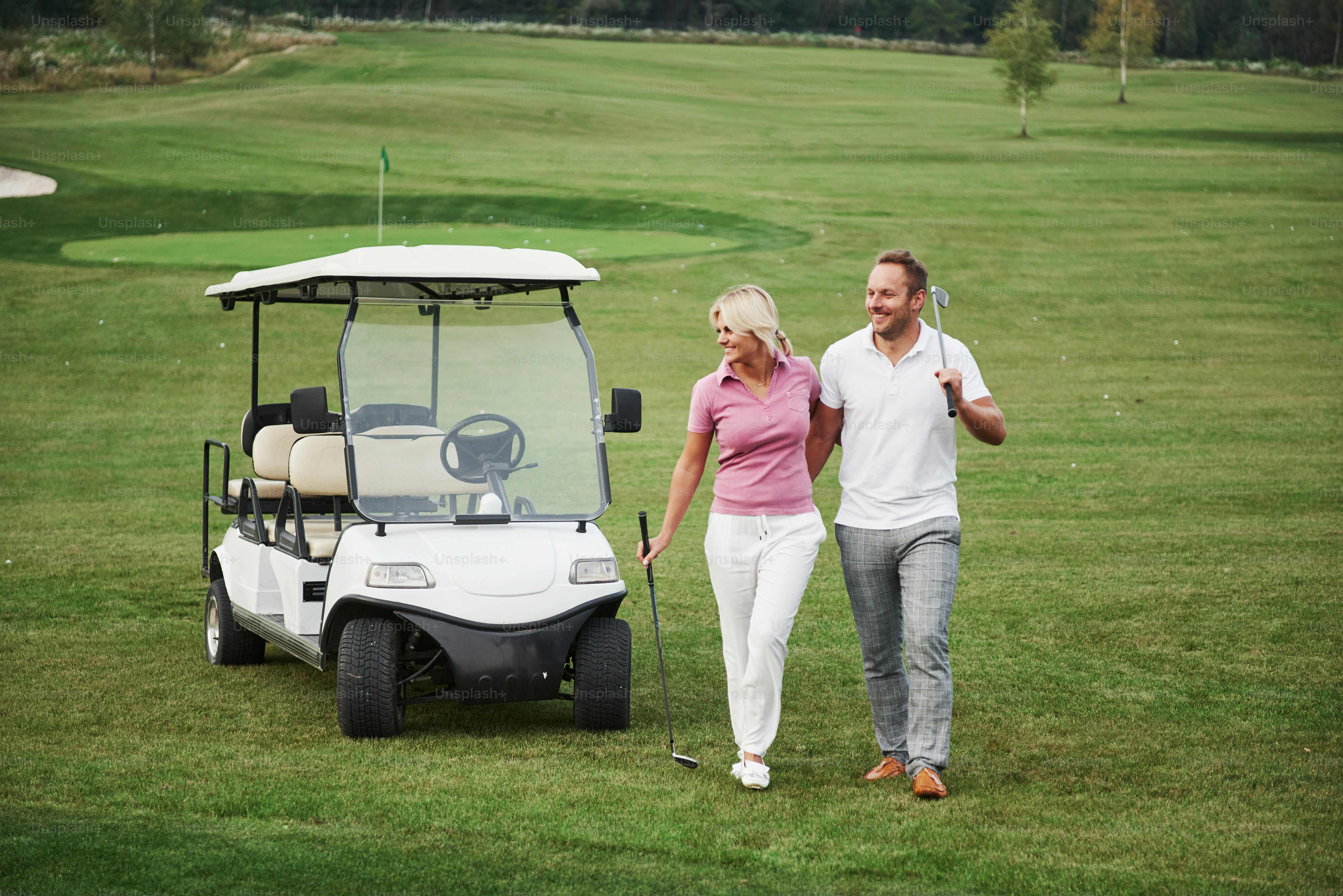 Two professional golfers, a woman and a man go together to the next hole. Lovers hug and smile, they have a date.