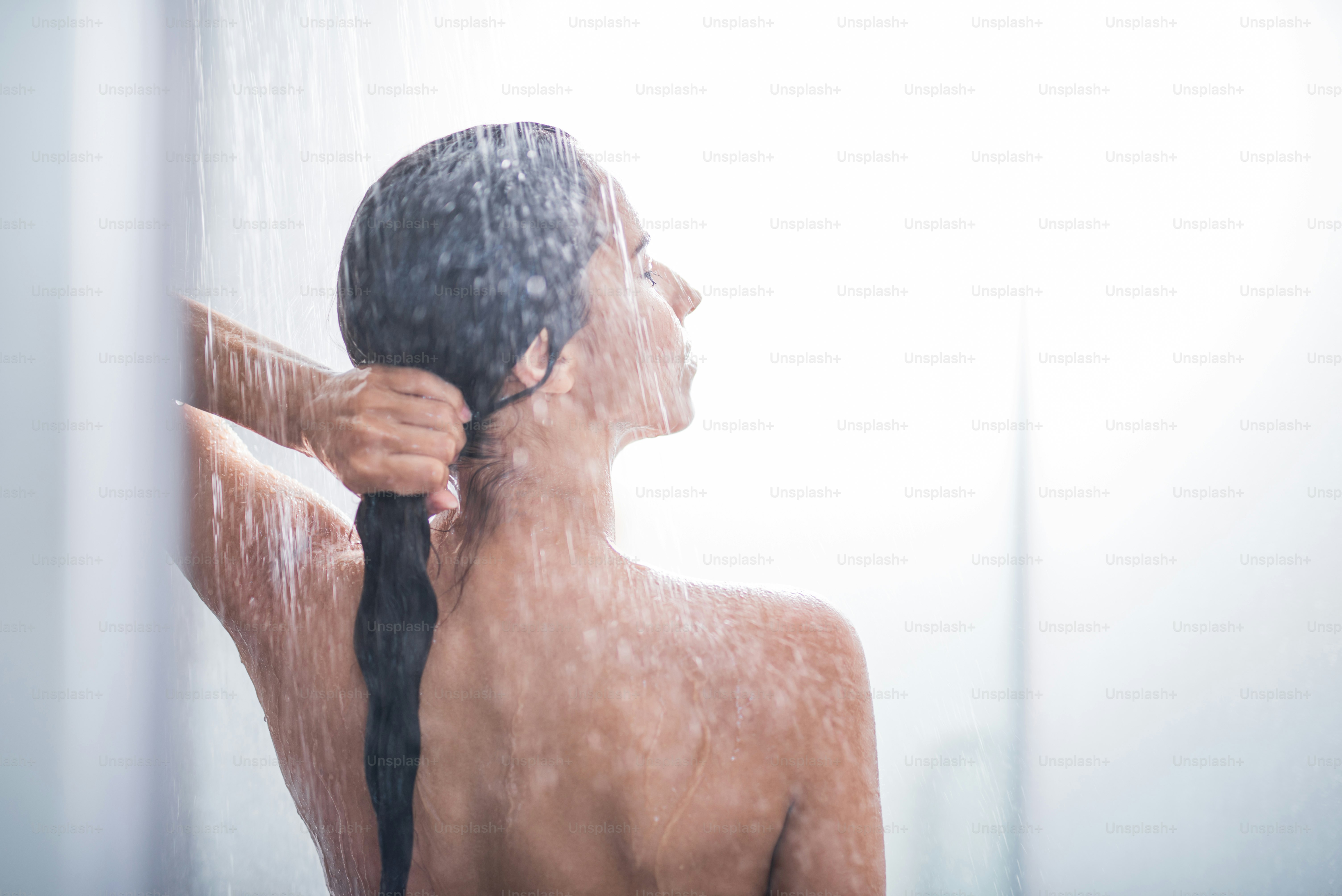 Side view orderly woman touching head and gesticulating arms while standing under stream of water