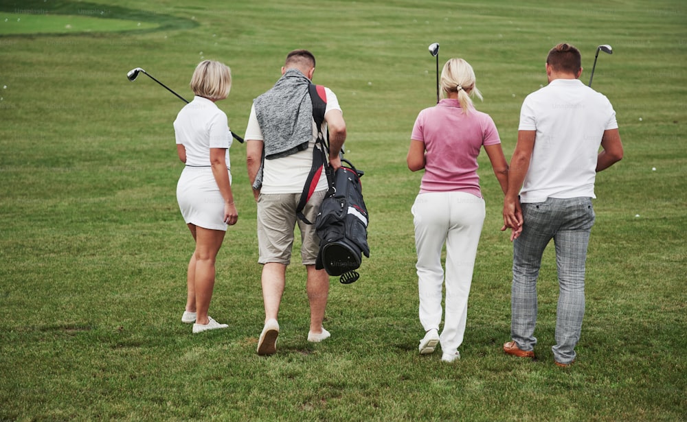 Un grupo de amigos con estilo en el campo de golf aprende a jugar un nuevo juego. El equipo va a descansar después del partido.