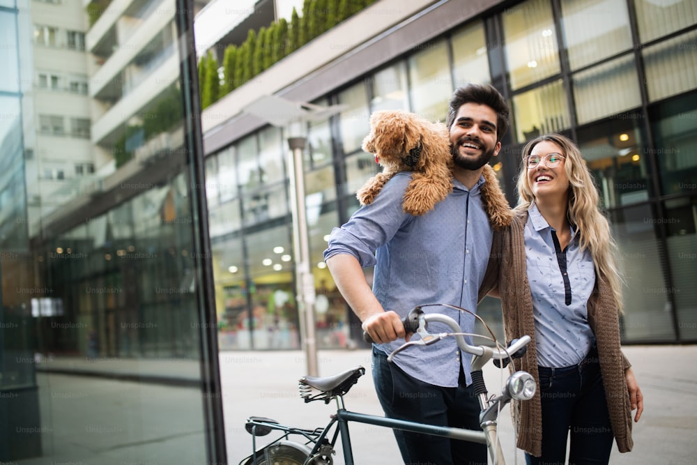 아름다운 낭만적 인 커플은 개와 자전거로 도시에서 휴식을 취하고 있습니다.