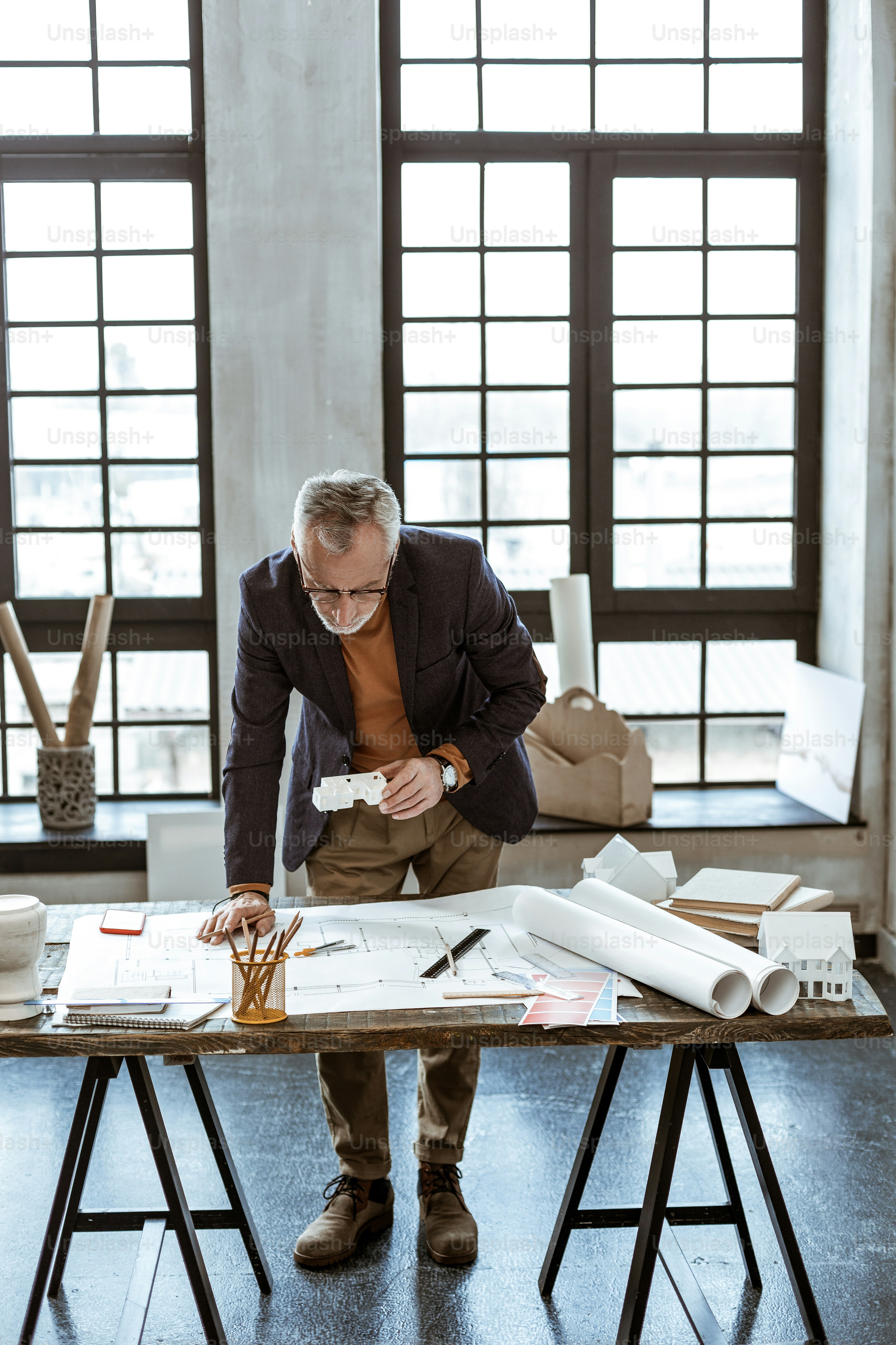 Designer mit Bleistift. Dunkeläugiger reifer Innenarchitekt, der Bleistift hält, während er Skizzen anfertigt