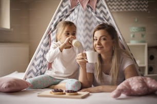 We like breakfast in bed. Mother and daughter having breakfast in bed.