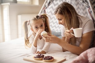 Milk is good for you. Mother and daughter having breakfast in bed.