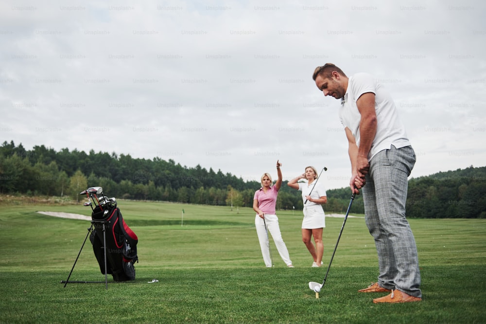 Un groupe d’amis élégants sur le terrain de golf apprend à jouer à un nouveau jeu.