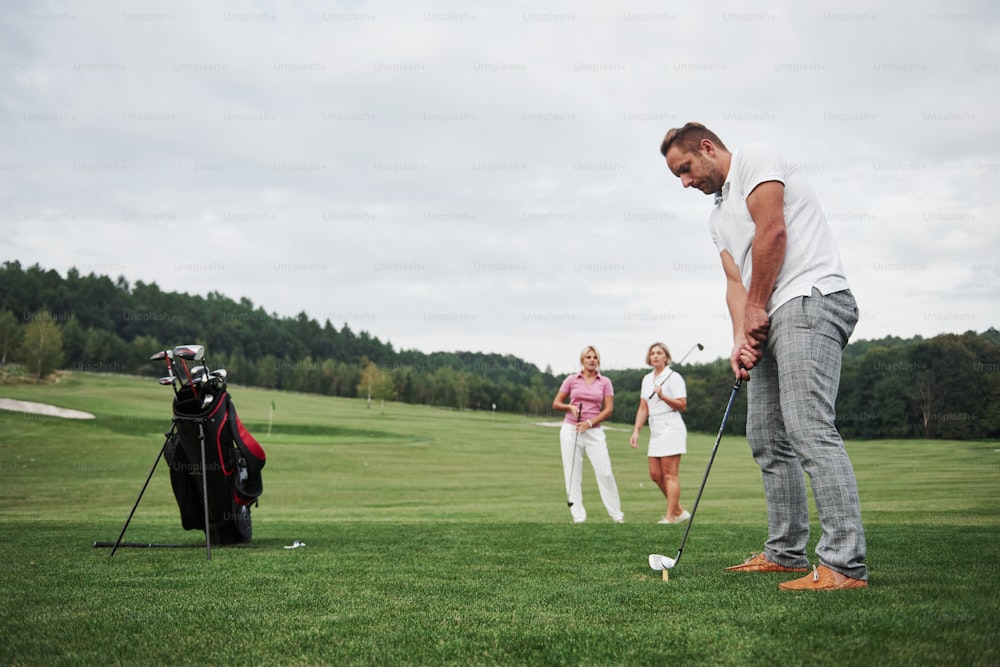 Un groupe d’amis élégants sur le terrain de golf apprend à jouer à un nouveau jeu.