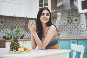A beautiful sports woman with fresh fruits and vegetables in the kitchen.