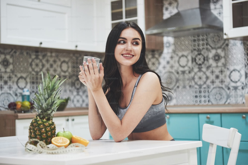 A beautiful sports woman with fresh fruits and vegetables in the kitchen.