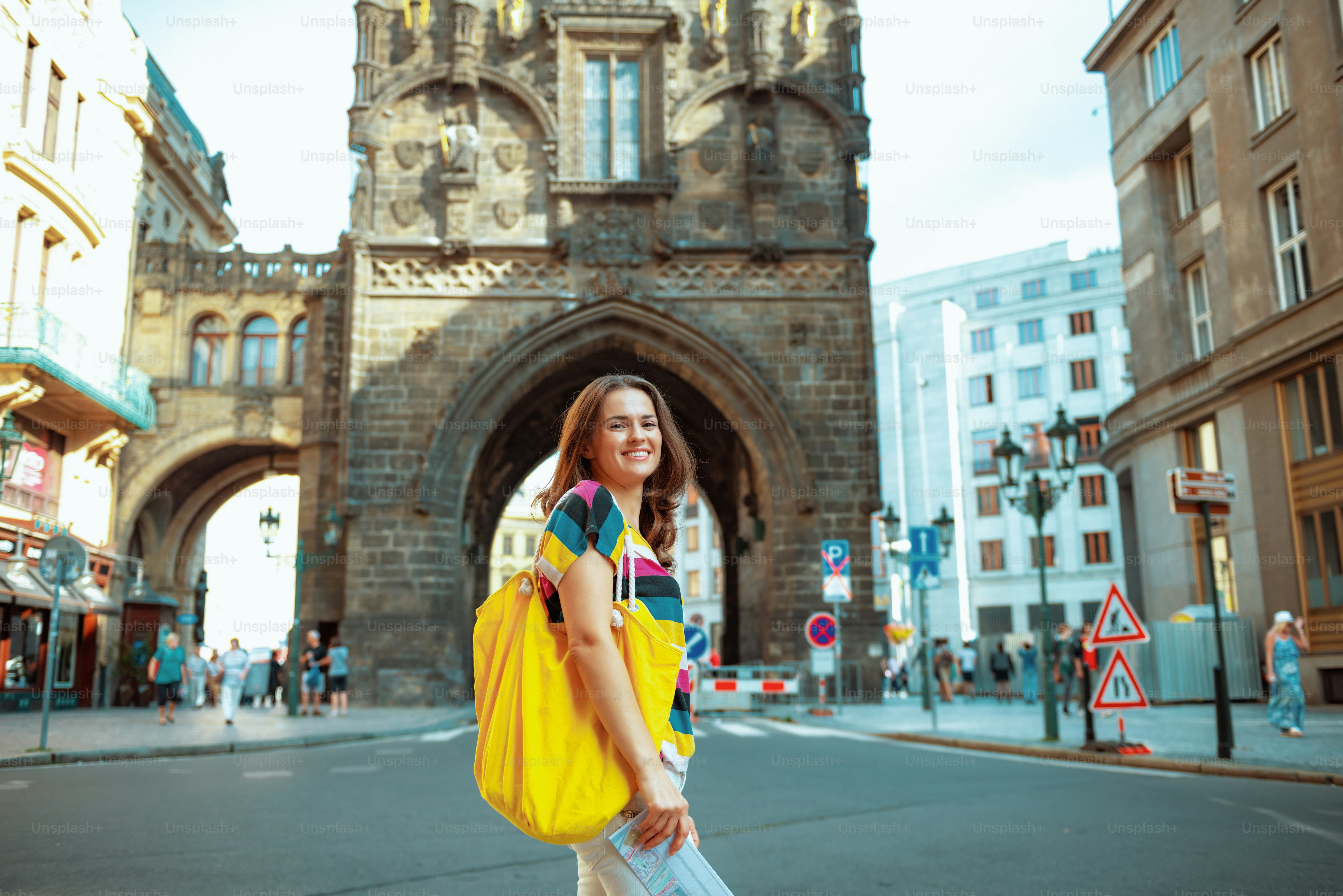 Excursionista sonriente de mujer moderna en camiseta a rayas coloridas en el frente de la Torre de la Pólvora en Praga, República Checa, que tiene excursión.