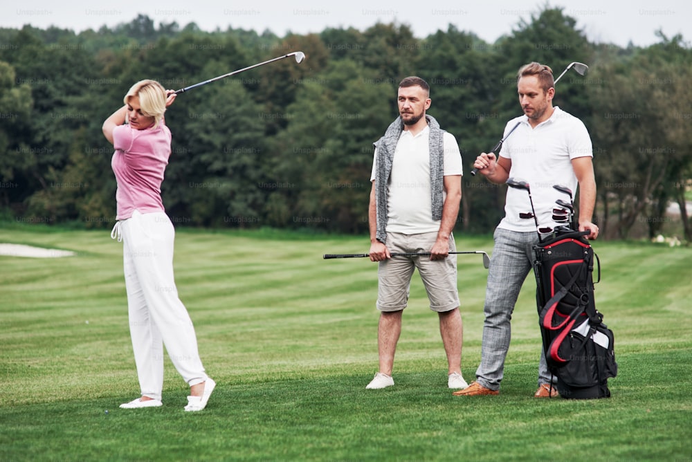 Trois amis passent du bon temps sur le terrain à jouer au golf et à regarder le coup.