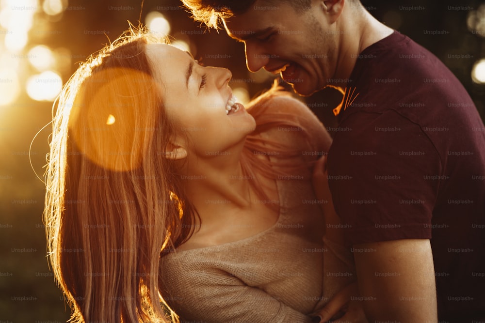Ritratto ravvicinato di una coppia caucasica che si diverte ad abbracciare e ridere contro il tramonto durante gli appuntamenti.