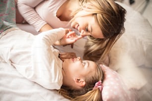 Hello mommy. Mother daughter playing in bed.