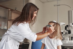 These device are suitable for you. Little girl tries new blue glasses in ophthalmologic office with female doctor.