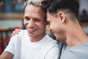 Smiling man embracing outgoing friend during conversation. Cheerful comrades talking together concept
