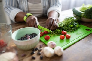 So tasty. Dark-skinned female cutting tomatoes while standing at the table