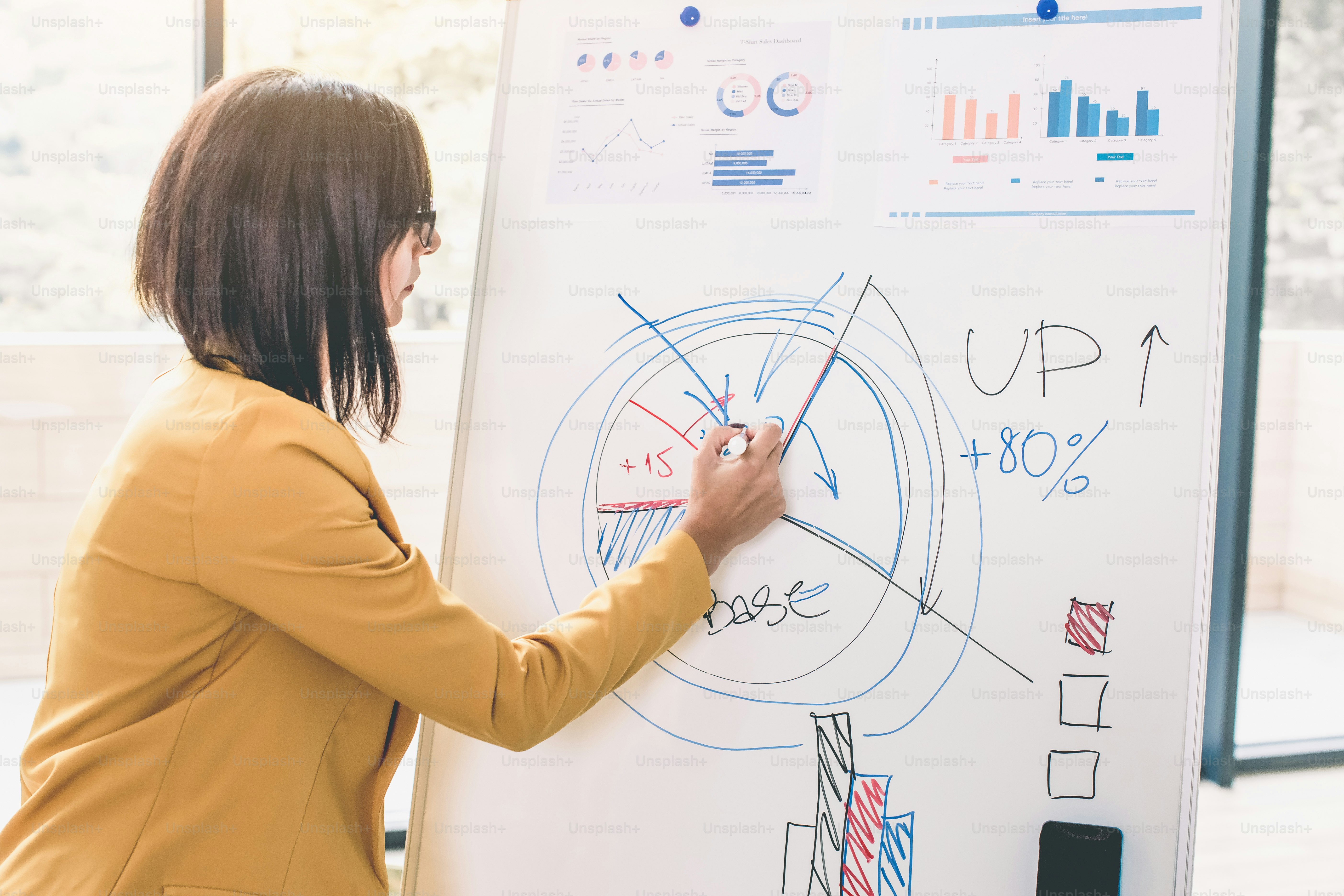 Femme d’affaires heureuse analysant un graphique sur un tableau blanc