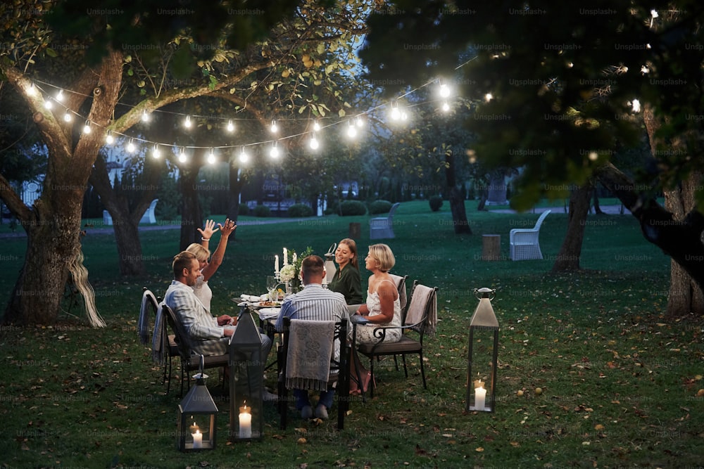 Active conversation. Evening time. Friends have a dinner in the gorgeous outdoor place.