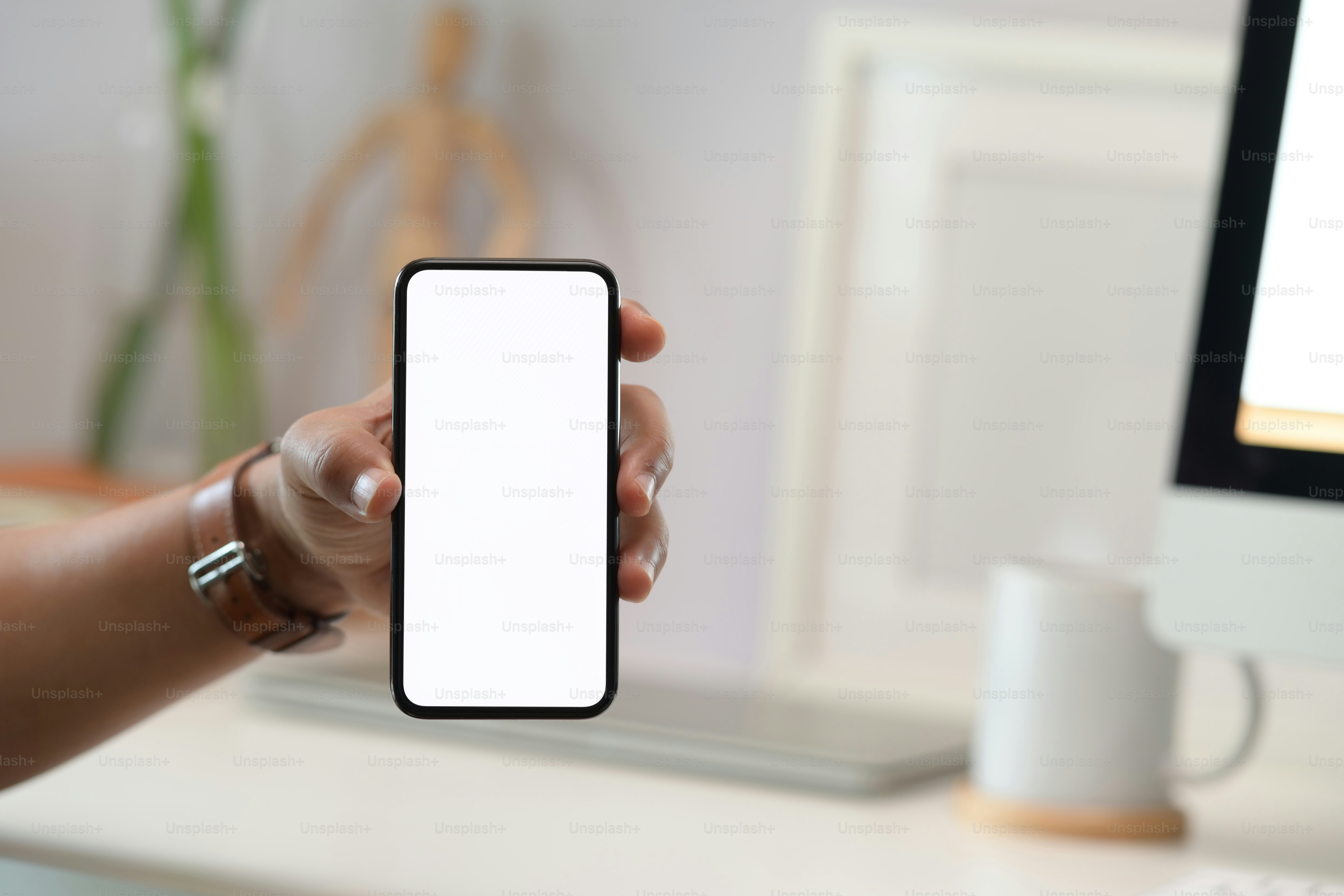 Hombre de negocios con la mano sosteniendo un teléfono móvil blanco en blanco en la oficina
